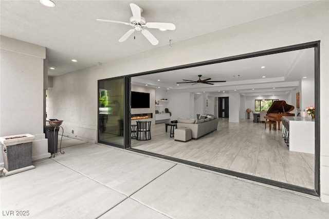 living room featuring ceiling fan and a tray ceiling