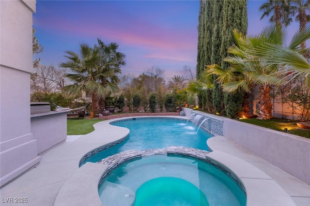 pool at dusk featuring an in ground hot tub