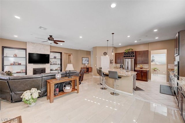 tiled living room featuring built in shelves, ceiling fan, and a fireplace