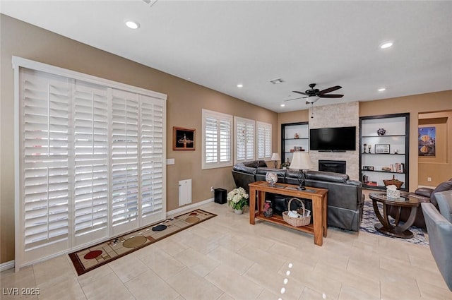 living room featuring ceiling fan, a fireplace, and light tile patterned floors