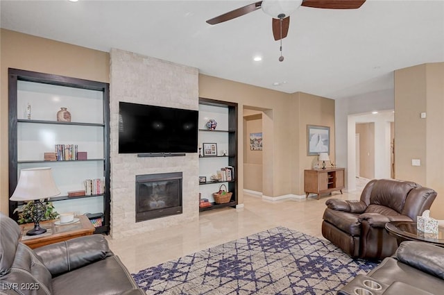 living room featuring ceiling fan, a fireplace, and built in features