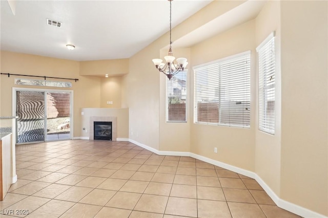 unfurnished living room with a tile fireplace, light tile patterned floors, and a chandelier