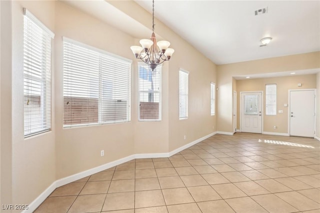 tiled empty room with plenty of natural light and an inviting chandelier