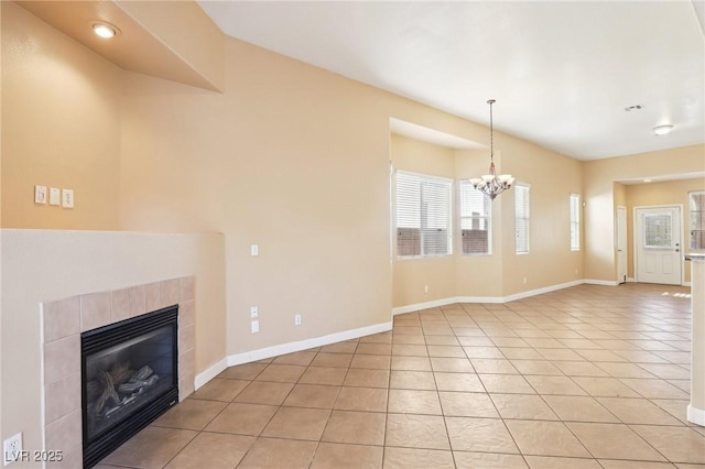 unfurnished living room featuring light tile patterned flooring, a tile fireplace, and a notable chandelier