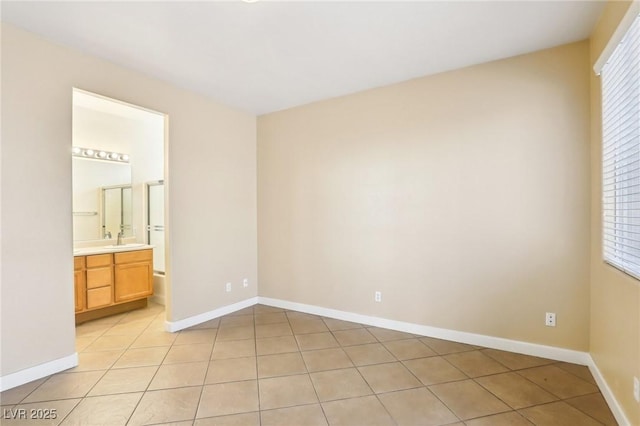 unfurnished bedroom featuring light tile patterned flooring, connected bathroom, and sink