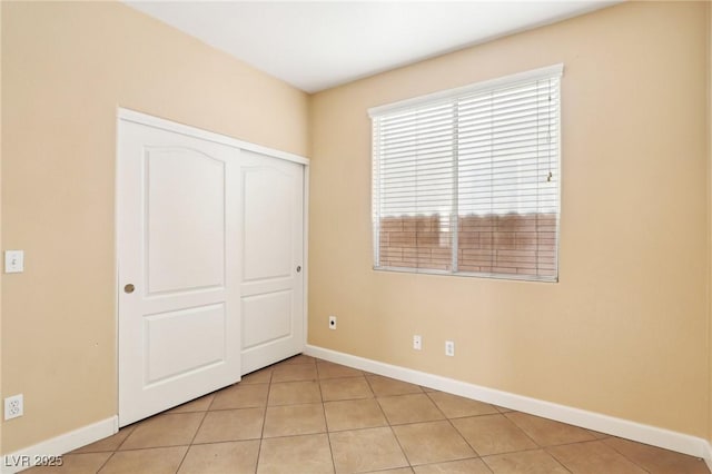 unfurnished bedroom featuring light tile patterned floors and a closet