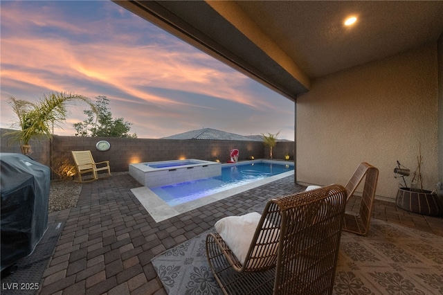 pool at dusk featuring grilling area, a patio, and an in ground hot tub