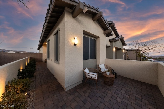 property exterior at dusk featuring a patio area