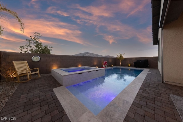 pool at dusk featuring an in ground hot tub