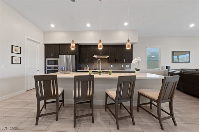 kitchen featuring stainless steel appliances, a breakfast bar, pendant lighting, and dark brown cabinetry