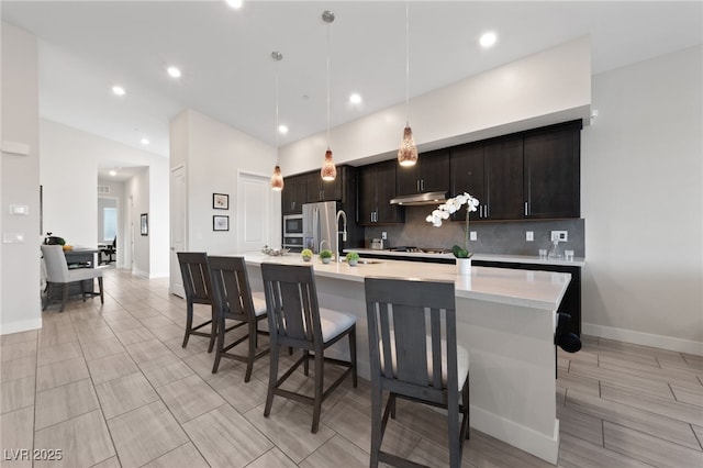 kitchen with decorative light fixtures, tasteful backsplash, stainless steel fridge, dark brown cabinetry, and gas stovetop