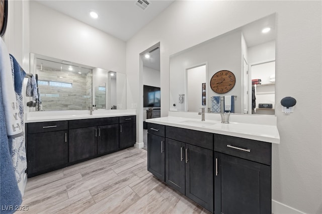 bathroom with vanity, wood-type flooring, and tiled shower