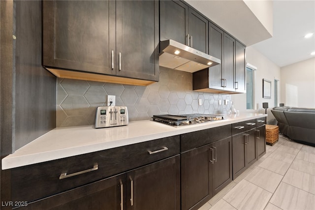 kitchen featuring stainless steel gas stovetop, dark brown cabinets, and decorative backsplash