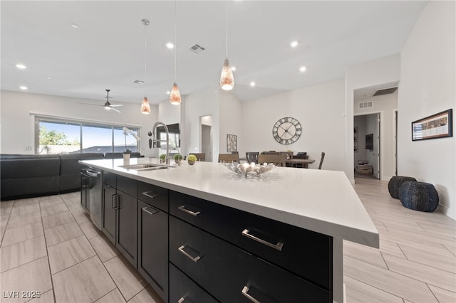 kitchen featuring sink, hanging light fixtures, dishwasher, ceiling fan, and a kitchen island with sink