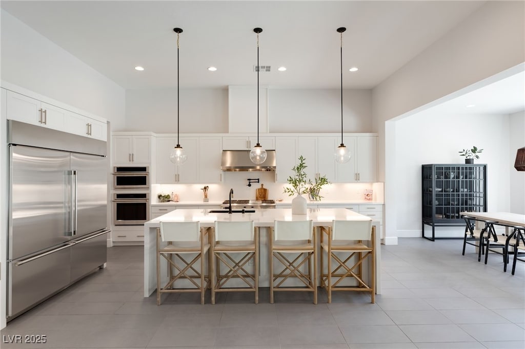 kitchen featuring a large island with sink, stainless steel appliances, a kitchen breakfast bar, and white cabinets