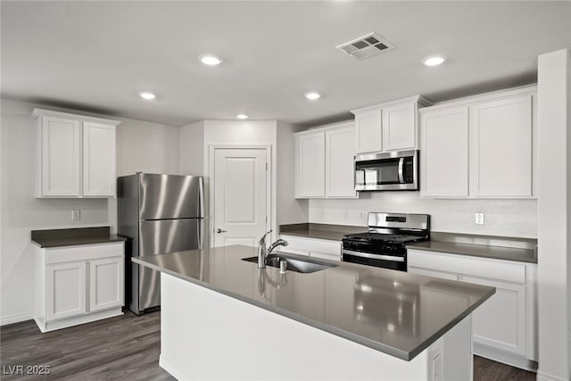 kitchen featuring sink, white cabinetry, stainless steel appliances, dark hardwood / wood-style floors, and a center island with sink