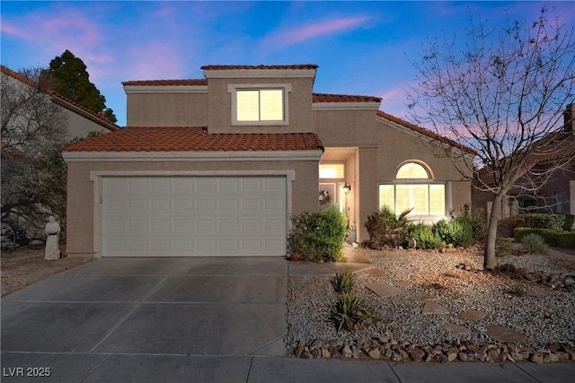 mediterranean / spanish home with a garage, concrete driveway, a tile roof, and stucco siding