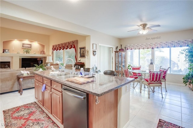 kitchen with a sink, open floor plan, stainless steel dishwasher, an island with sink, and plenty of natural light