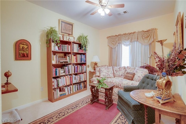 sitting room with visible vents, carpet floors, and a ceiling fan