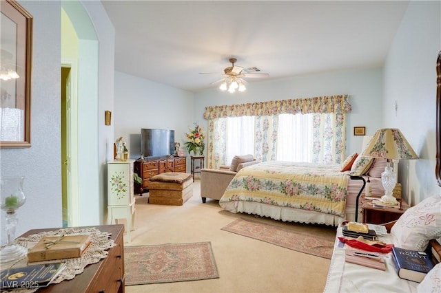 bedroom featuring arched walkways, ceiling fan, and light carpet