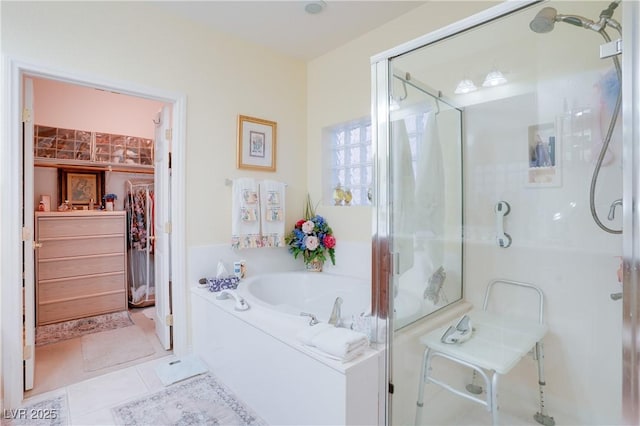 bathroom with tile patterned flooring, a garden tub, a walk in closet, and a shower stall