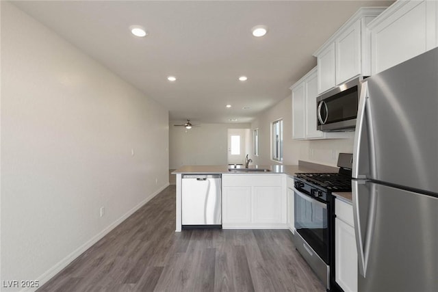 kitchen featuring stainless steel appliances, kitchen peninsula, and white cabinets