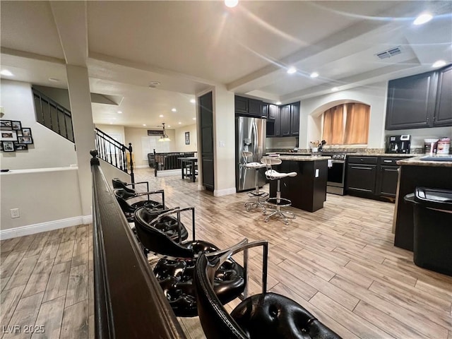 kitchen featuring a kitchen island, appliances with stainless steel finishes, a breakfast bar, beamed ceiling, and sink