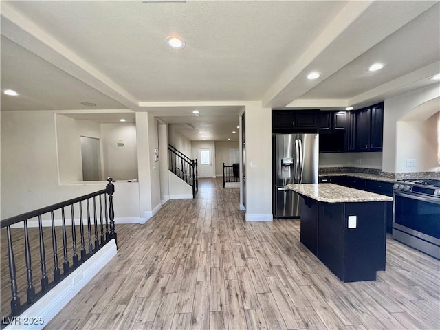 10618 Timber Stand St, Las Vegas, NV 89183 - kitchen with stainless steel appliances, light wood-type flooring, arched walkways, a center island, and dark cabinetry