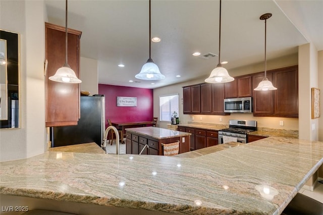 kitchen with appliances with stainless steel finishes, a breakfast bar, pendant lighting, sink, and kitchen peninsula