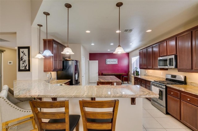 kitchen featuring a breakfast bar, pendant lighting, sink, kitchen peninsula, and stainless steel appliances