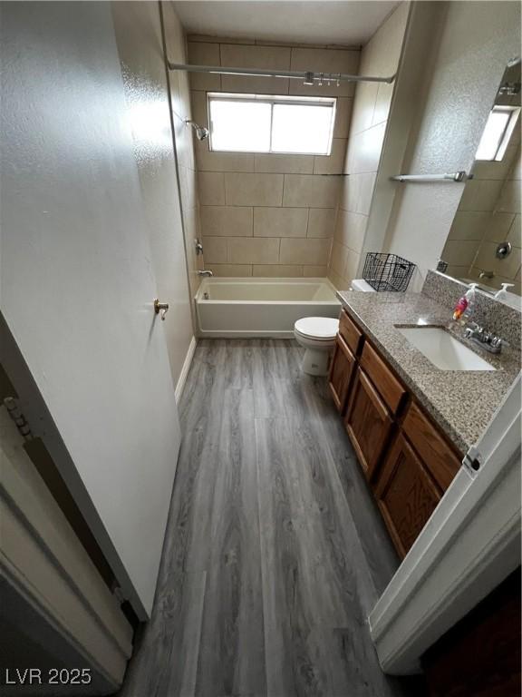 full bathroom featuring vanity, hardwood / wood-style flooring, toilet, and tiled shower / bath combo