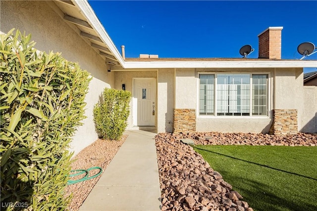 view of exterior entry featuring a lawn