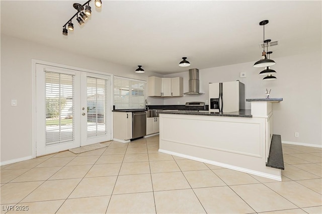 kitchen featuring pendant lighting, wall chimney range hood, appliances with stainless steel finishes, white cabinets, and french doors