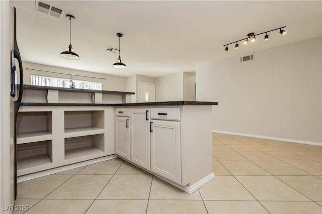 kitchen with dark stone countertops, light tile patterned floors, track lighting, pendant lighting, and white cabinets