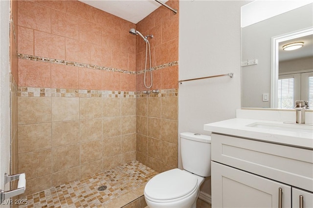 bathroom with vanity, toilet, and a tile shower