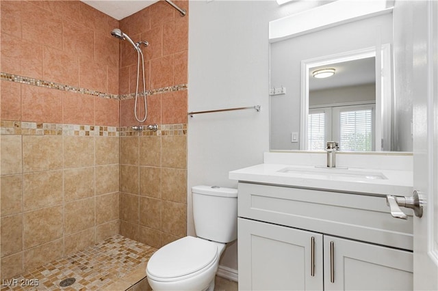 bathroom with tiled shower, vanity, and toilet