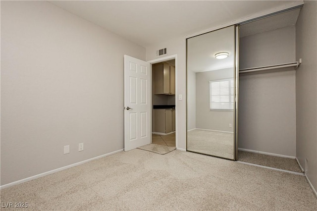 unfurnished bedroom with light colored carpet and a closet