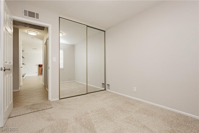 unfurnished bedroom featuring light colored carpet and a closet