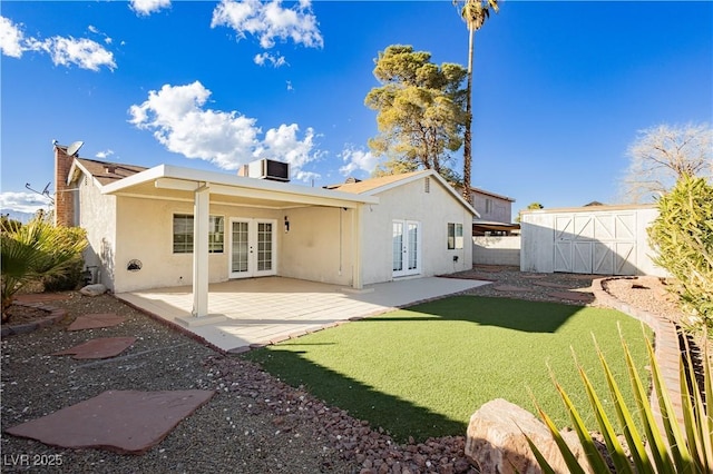 rear view of property with a shed, a yard, a patio area, central air condition unit, and french doors