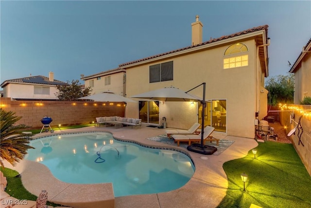 back house at dusk featuring an outdoor living space and a patio