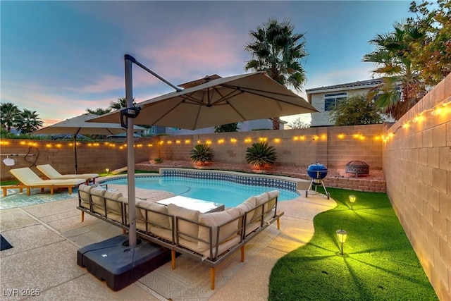 pool at dusk featuring grilling area and a patio area