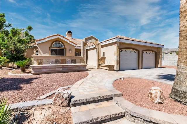 mediterranean / spanish-style home featuring a tile roof, concrete driveway, an attached garage, and stucco siding