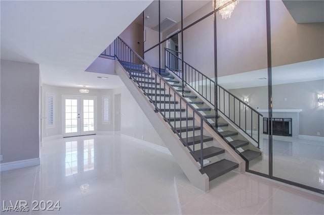 stairs featuring french doors, a towering ceiling, and tile patterned floors