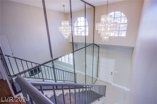 stairs with an inviting chandelier and a high ceiling