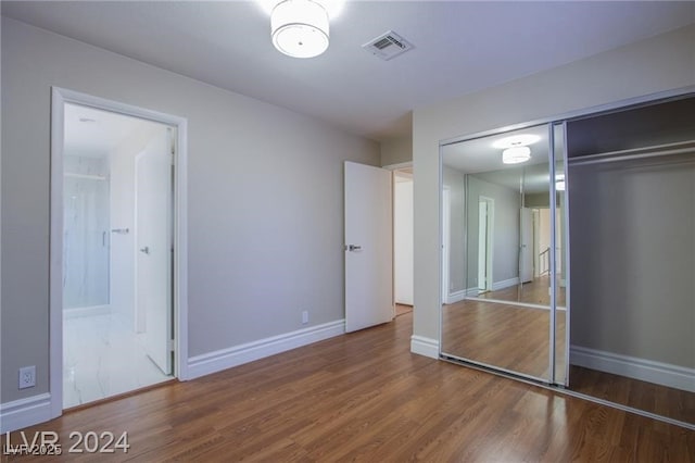 unfurnished bedroom with hardwood / wood-style floors, a closet, and ensuite bathroom