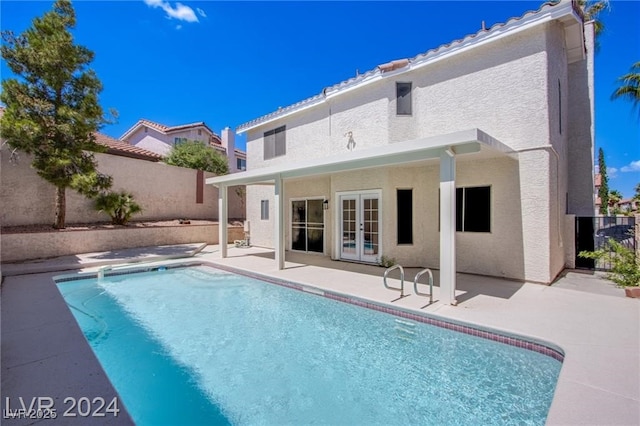 rear view of house with a fenced in pool and a patio