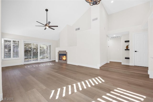 unfurnished living room featuring ceiling fan, high vaulted ceiling, and light wood-type flooring