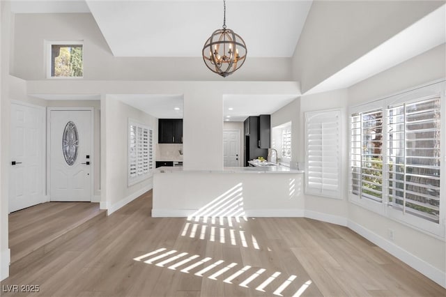 entryway featuring high vaulted ceiling, an inviting chandelier, and light hardwood / wood-style flooring