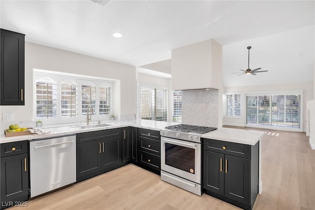 kitchen with stainless steel appliances, sink, light hardwood / wood-style floors, and kitchen peninsula