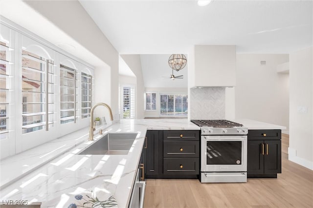 kitchen featuring sink, stainless steel gas range, light hardwood / wood-style flooring, backsplash, and light stone counters